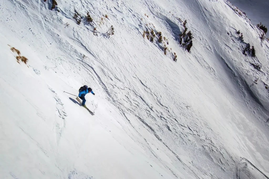Expert freeride skier charging down through steep slope