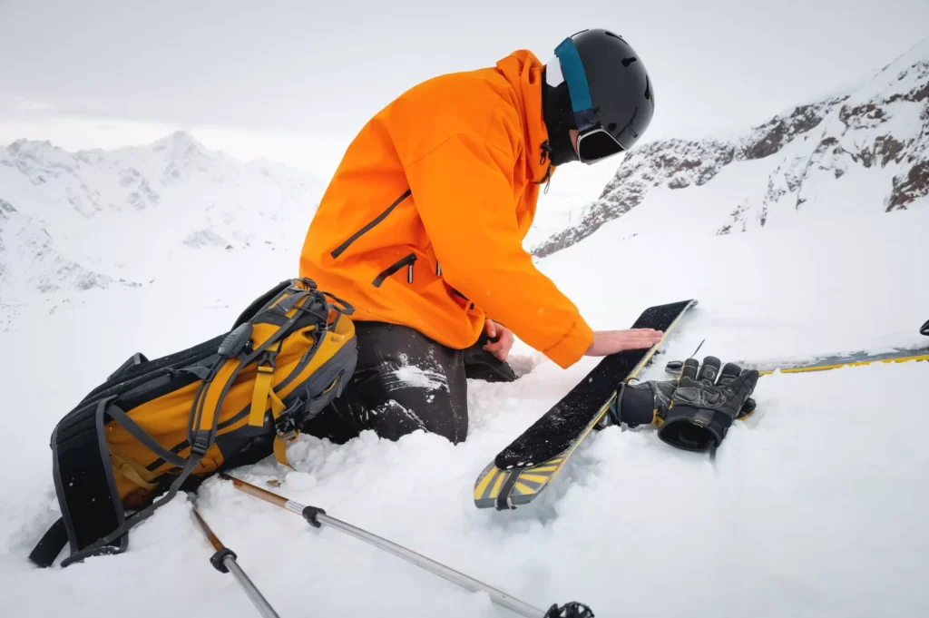 Turista sciatore ripara gli sci in montagne innevate. Neve e attività invernali, sci alpinismo in montagna.